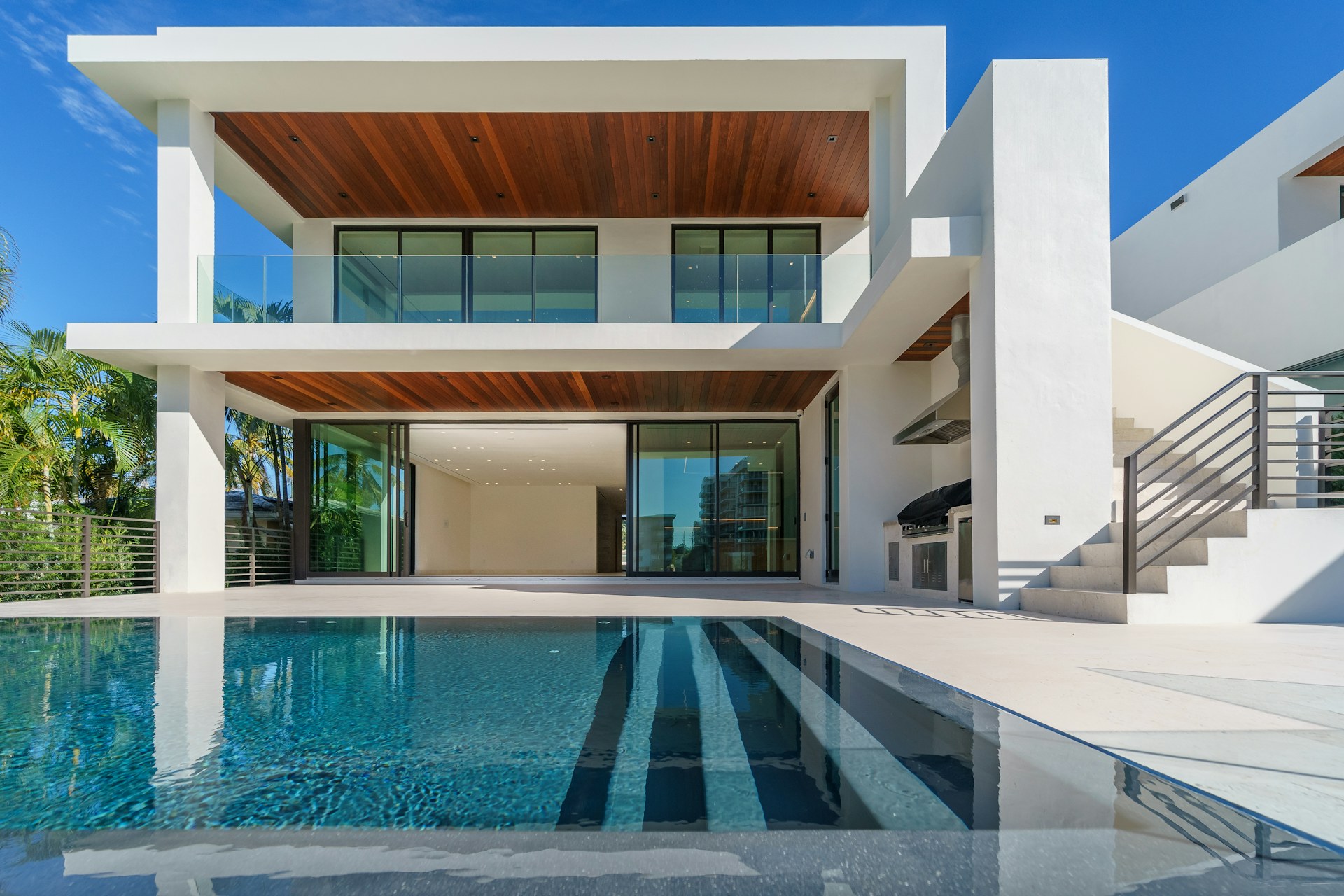 Contemporary white villa with illuminated windows and a blue swimming pool