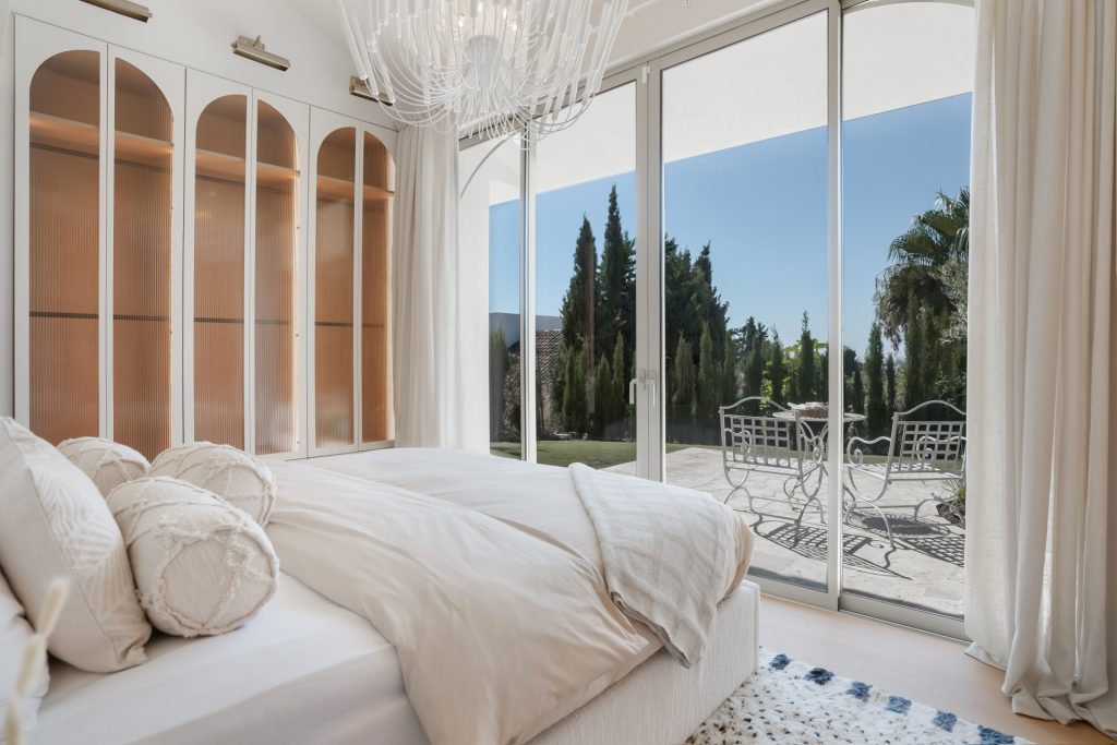 Bedroom opening onto a terrace through full-height glazing — Los Naranjos Garden Residence