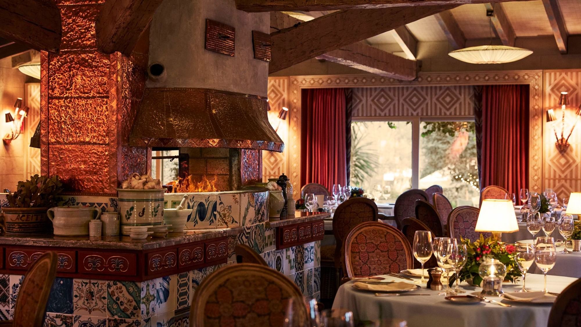 The Grill dining room at Marbella Club, with set tables, tiled fireplace and timber ceiling