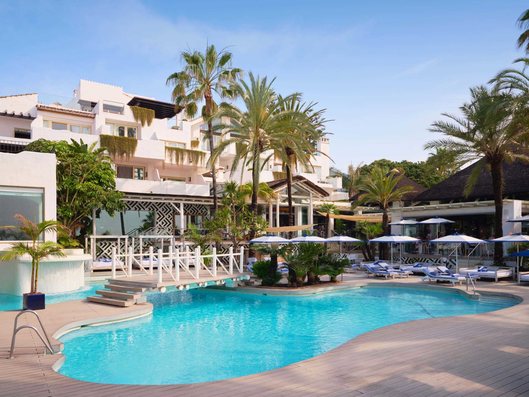 Puente Romano resort pool beside Sea Grill, with palms and white hotel buildings