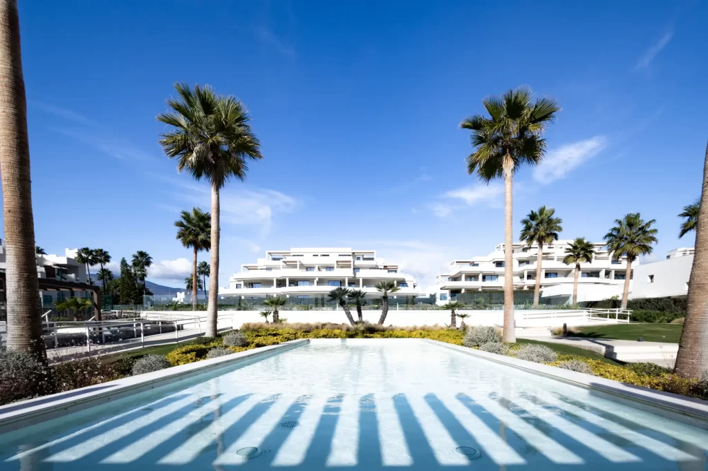 Velaya’s white residential buildings, landscaped grounds and palm trees beyond a shallow pool